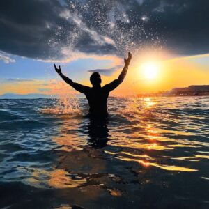 Silhouette of a person splashing water at sunset on a beach in Antalya, Turkey.