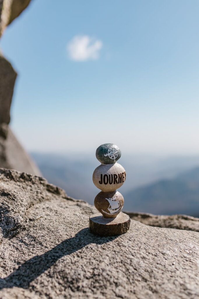 A stack of rocks with 'Journey' engraved, set against a serene mountain backdrop.